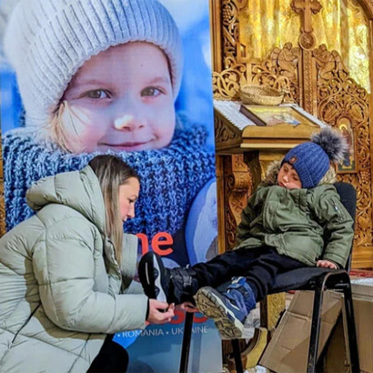 woman putting shoes on child