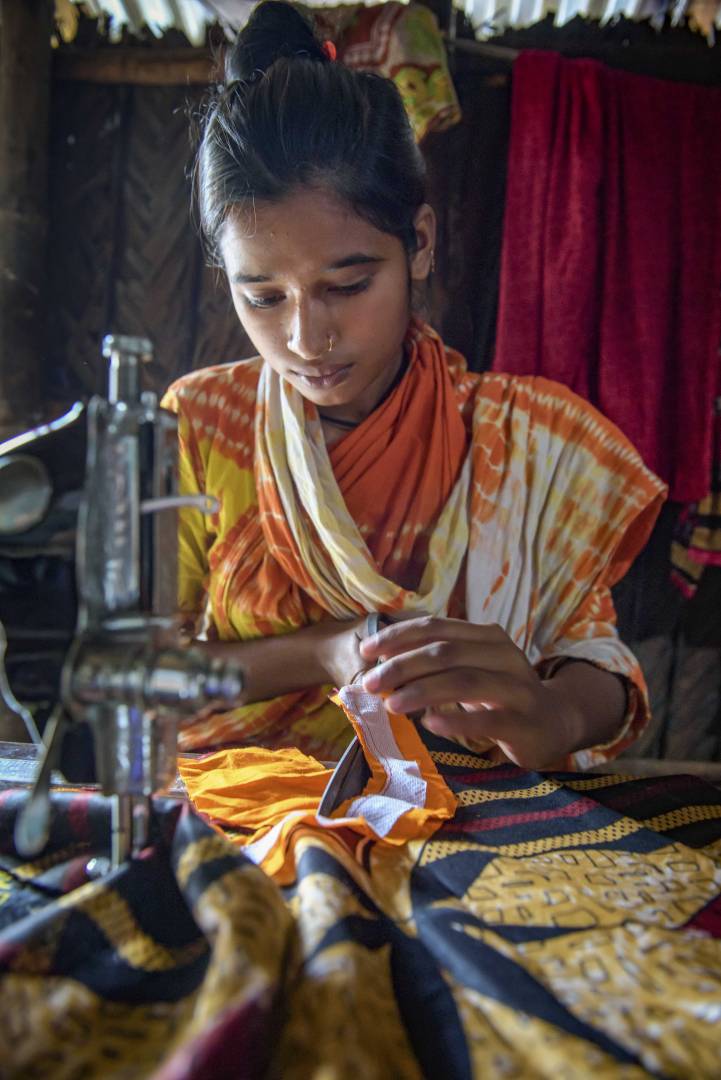 Bangladesh Hope Child Protection ELO Choity, 15, makes a dress using the sewing machine she received through an ELO child protection program in Bangladesh. She dropped out of school at age 13 to help support her family. The program helped children who were working return to school, or for those far behind like Choity, it provided life-skills training for safe work.