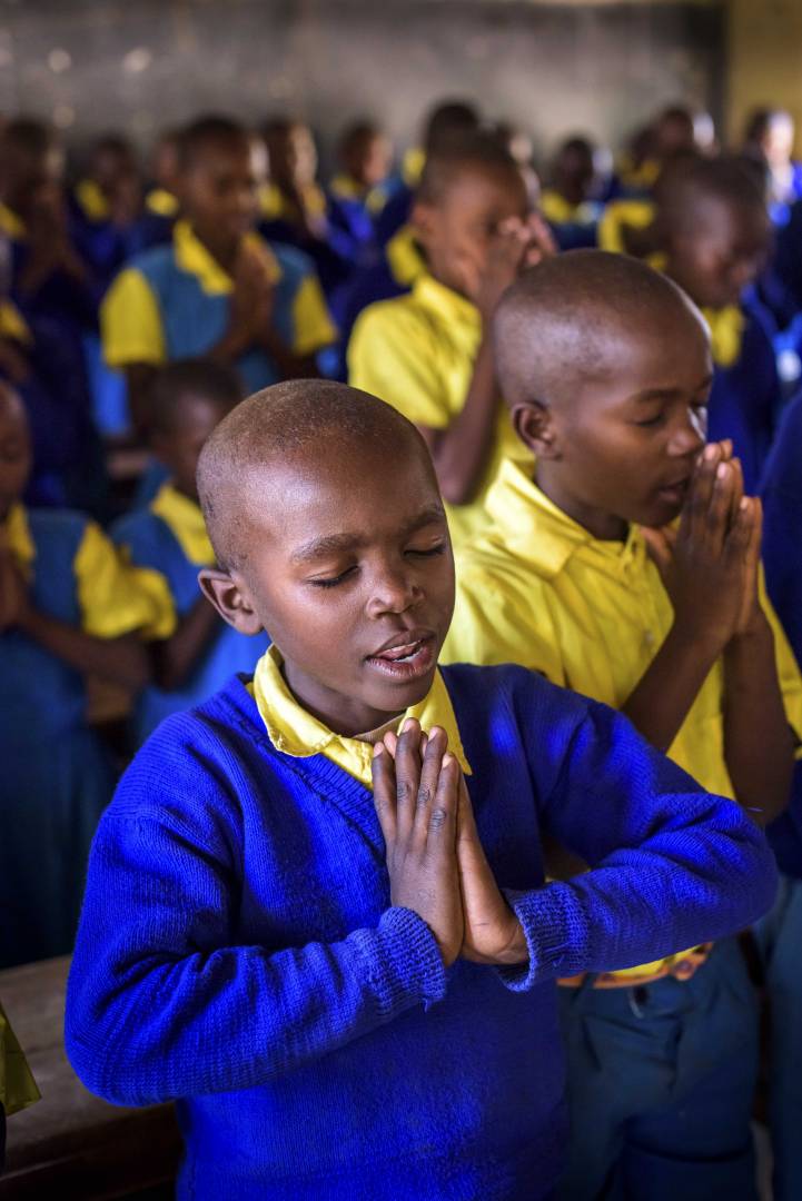 Kenya Hope Christian Discipleship Students pray together at a Bible club meeting in Kenya. The students, many of whom are sponsored, learn Bible verses, sing, hear the Word of God, and plant and care for fruit trees through the ELO Christian discipleship program.