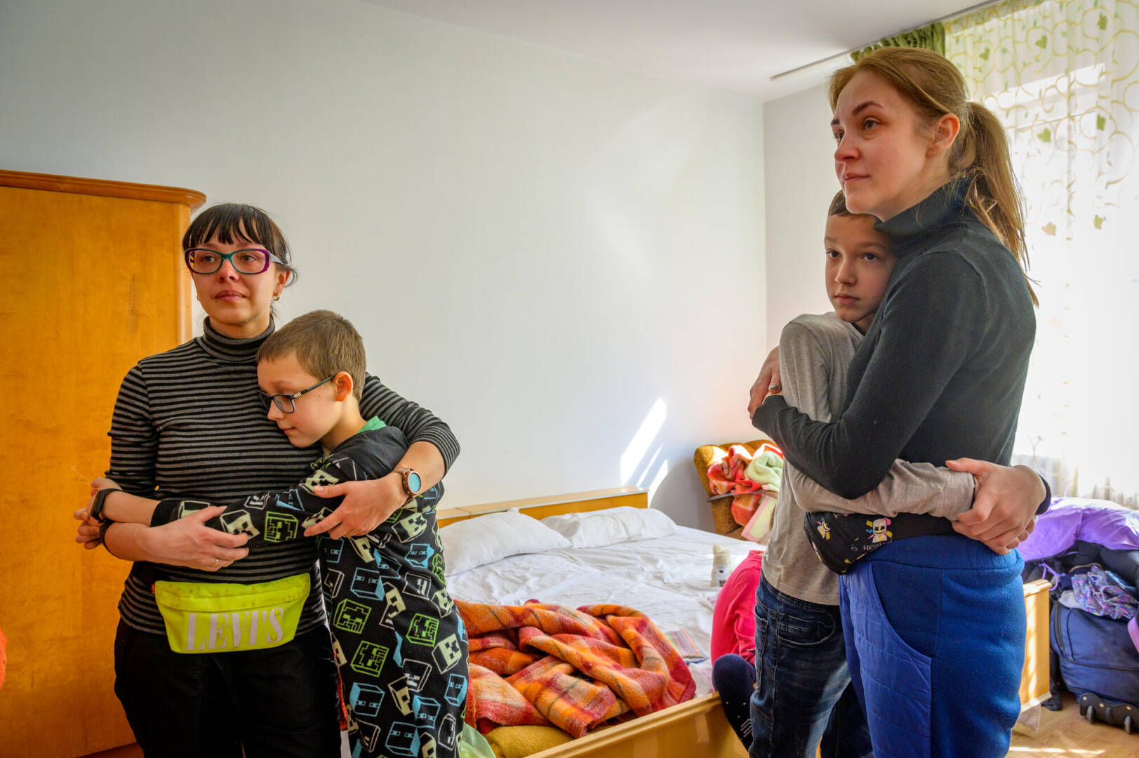 Sons console their moms Two sisters, both moms, are hugged by their sons as their eyes fill with tears.