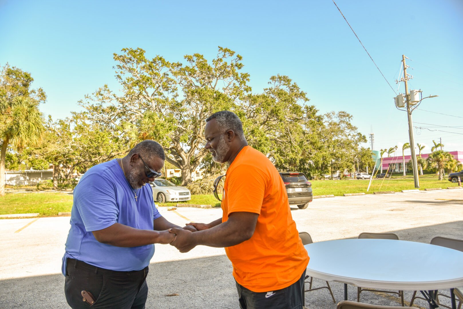 Two men face each other holding hands and praying.