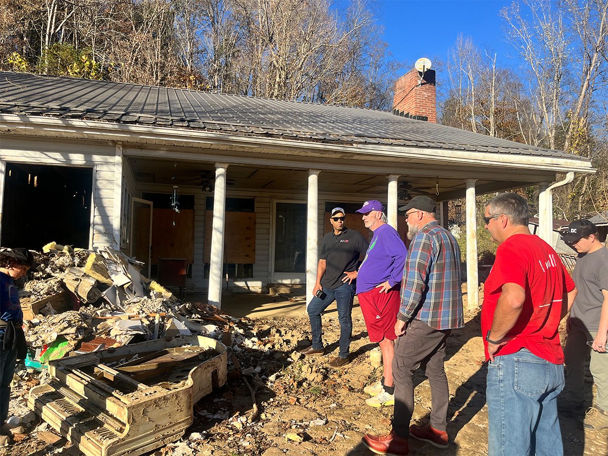 men looking at a destroyed house