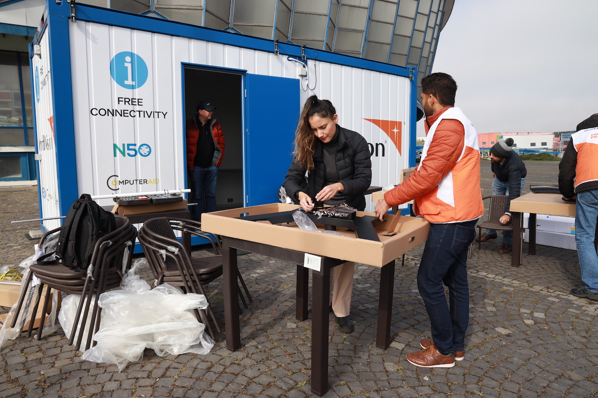 Team sets up tables in front of a trailer that says "free connectivity" and has logos for World Vision, N50, and ComputerAid