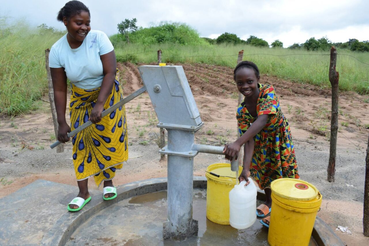 Loveness and her daughter pump clean water from a water point near their home.