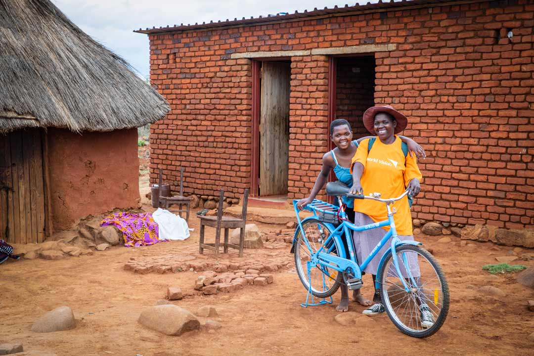 A woman stands with a bike given to her by UNICEF