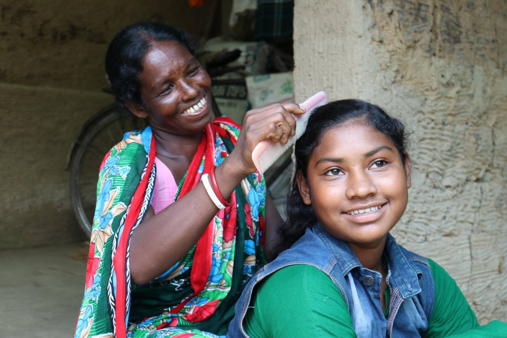 Hupni and daughter A mother smiles while she combs her daughter’s hair.