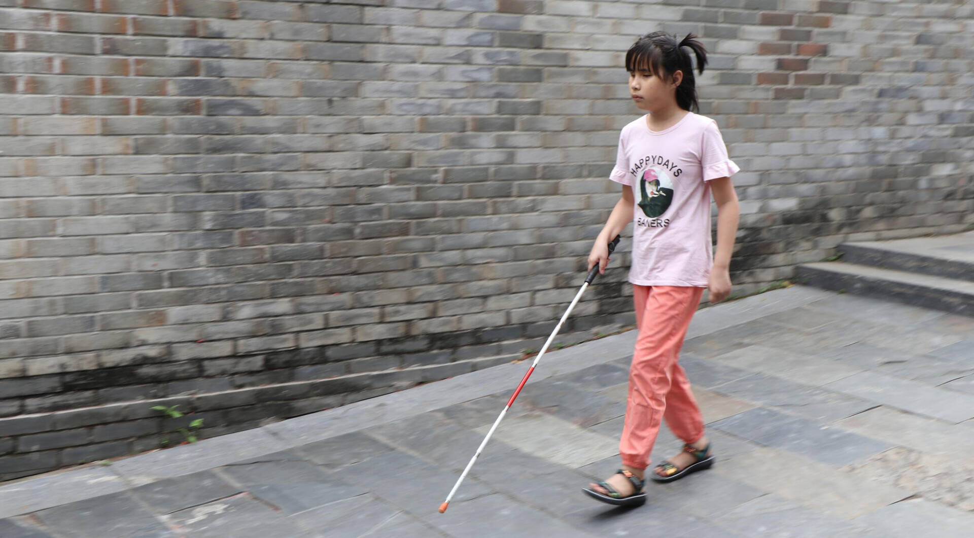 Xiaobing A Chinese girl takes a step with guidance from her walking stick.