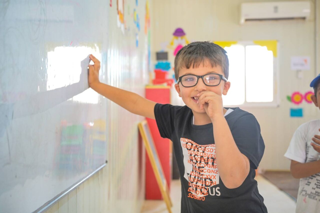 Zaid leans on a white board at World Vision&rsquo;s Early Child Education Center in Azraq Refugee Camp in Jordan. 