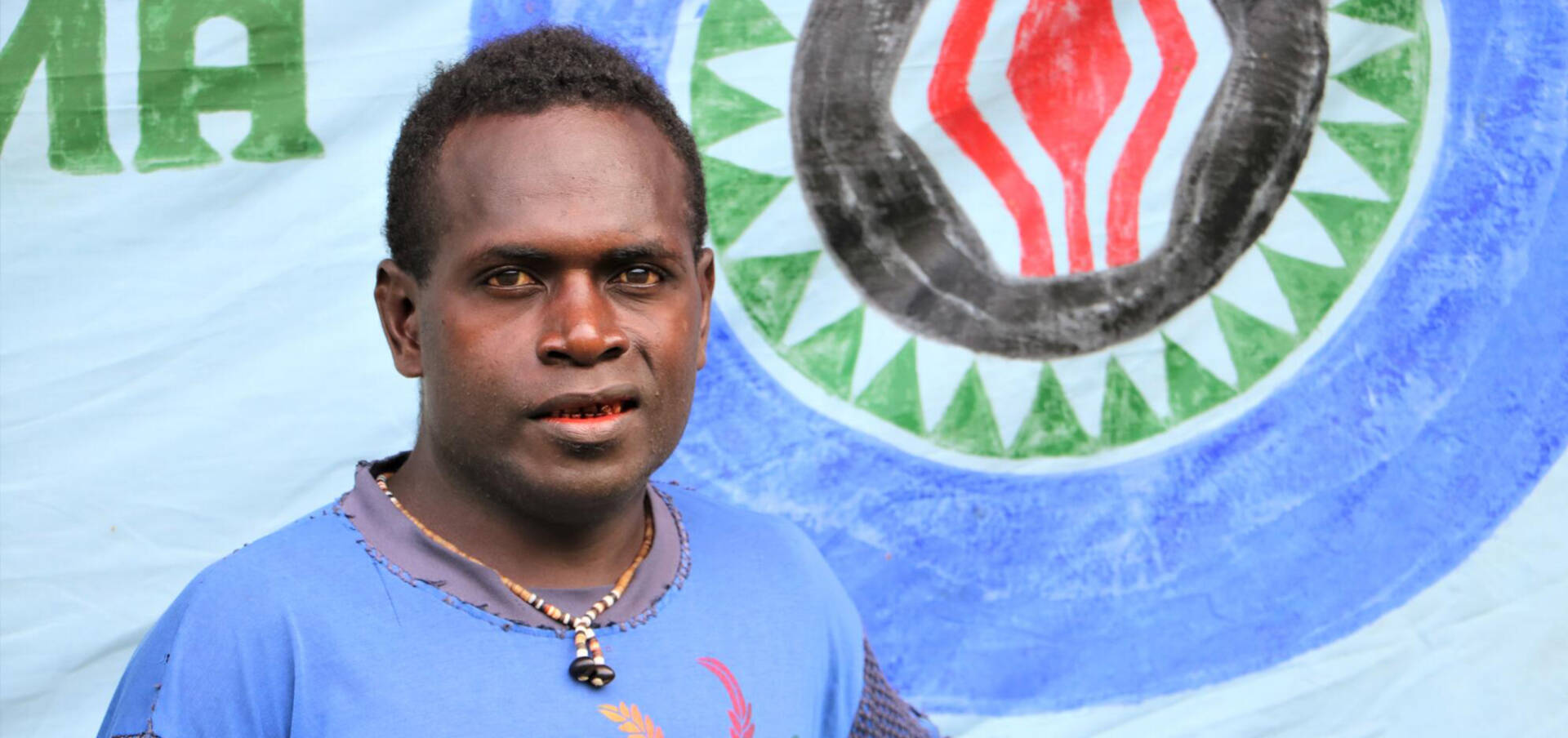 Community leader George A Papua New Guinean man in a blue T-shirt looks to the camera.