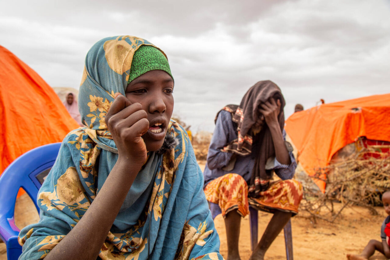 A girl dressed in a patterned blue veil sits in a camp in southern Somalia.