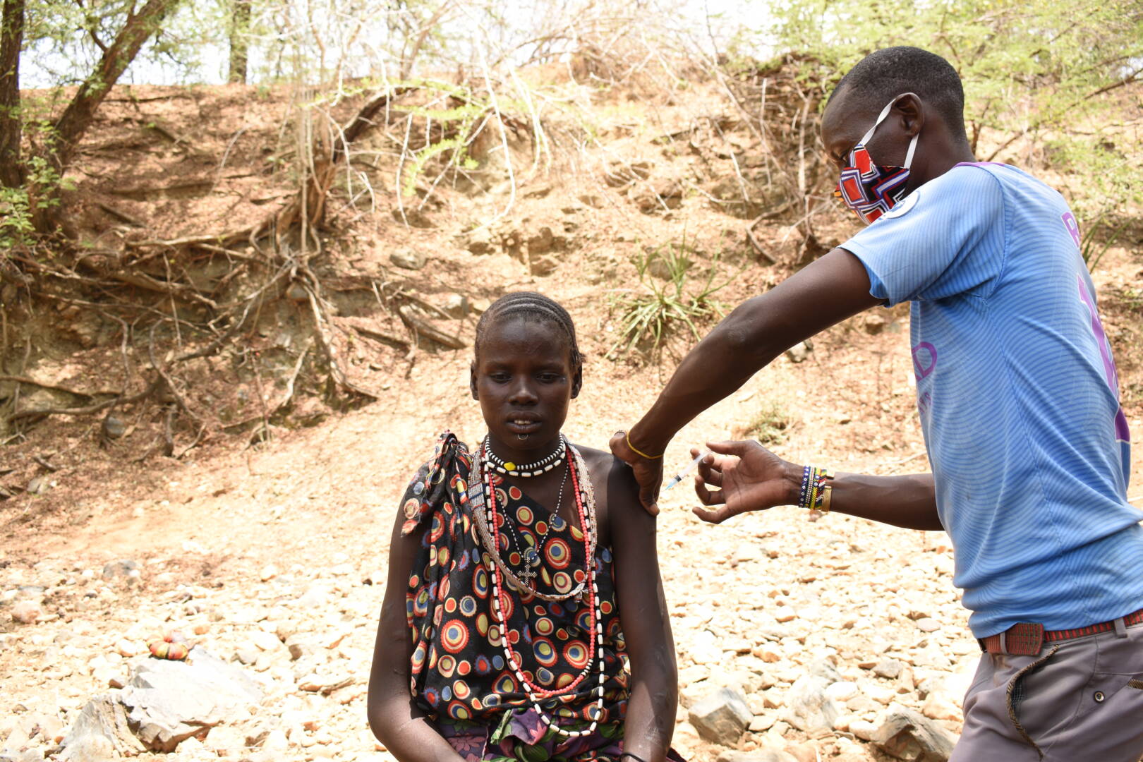 What is the coronavirus? Facts, symptoms, and how to help A woman in South Sudan sits and gets a vaccine from a man wearing a mask.