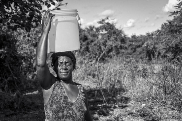 Maves stands with a 20-liter bucket that&rsquo;s used to collect water
