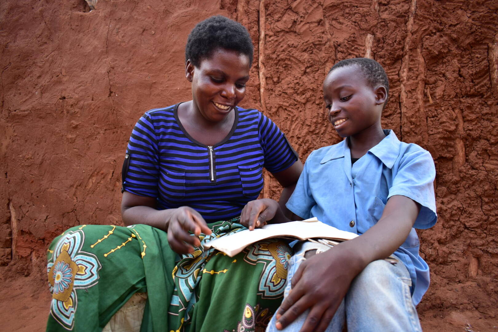 Lonely and Swangirai Lonely looks at an open booklet with her stepson, Swangirai.
