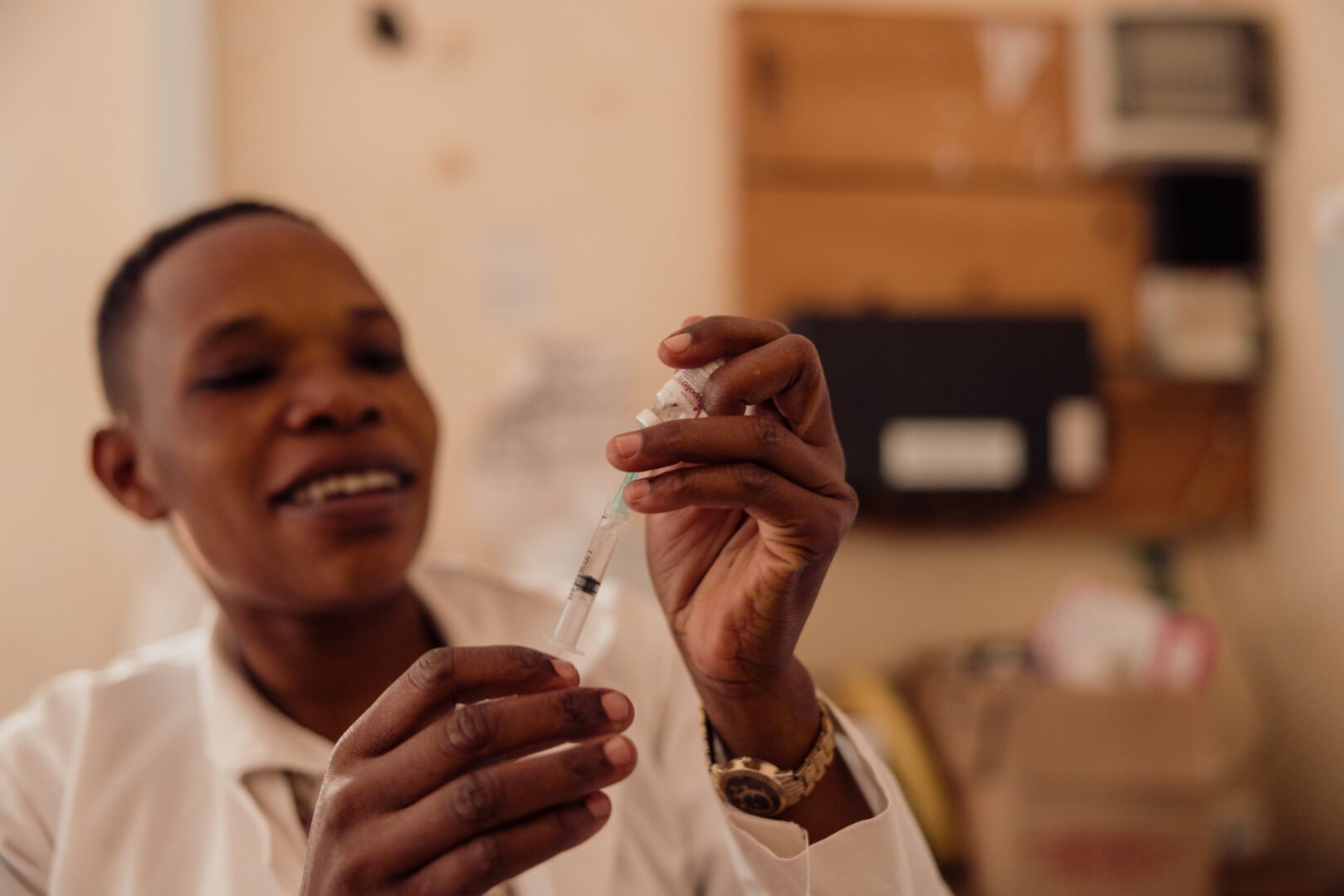A person in a white lab coat holds a syringe.