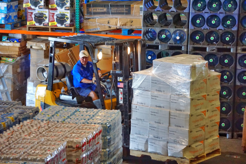 A man uses a forklift to unload boxes with the World Vision logo at warehouse.